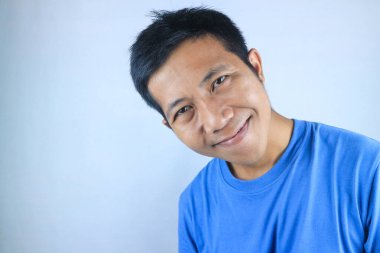 Gülümseyen yüz ifadesi genç Asyalı adam kameraya bakarken mutlu, beyaz arka planda soyutlanmış.