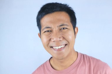 Gülümseyen yüz ifadesi genç Asyalı adam kameraya bakarken mutlu, beyaz arka planda soyutlanmış.