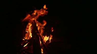Yakın plan, alevler. Gece ateşi, odunlar yanıyor, kıvılcımlar uçuşuyor.