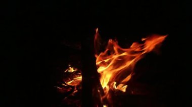 Yakın plan, alevler. Gece ateşi, odunlar yanıyor, kıvılcımlar uçuşuyor.