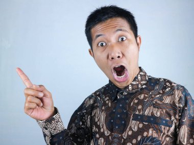Vay canına, şaşırmış surat ifadesi. Batik kıyafetler giyen Asyalı adam kameraya bakarken yüzünü gösteriyor.