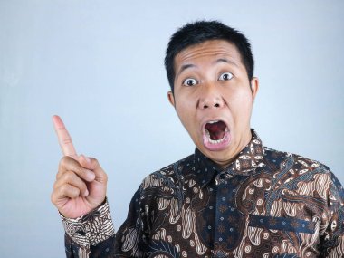 Vay canına, şaşırmış surat ifadesi. Batik kıyafetler giyen Asyalı adam kameraya bakarken yüzünü gösteriyor.