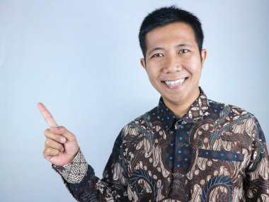 Batik giysiler giymiş Asyalı bir adamın gülümseyen ifadesi.