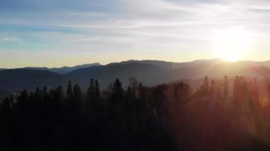 Dağlarda gün batımı. Güneş bulutların arasından ışıldıyor.