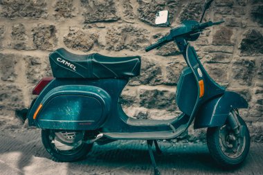 Şehrin caddesinde park etmiş mavi scooter.