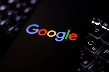 Kherson Reg, Ukrayna 19 Eylül 2024 'te yakın plan Google logosu aydınlatmalı dizüstü bilgisayarın klavyesinde duran akıllı telefon ekranında görüntülendi. 