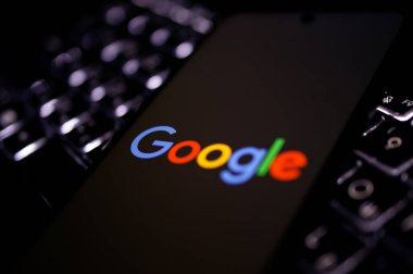 Kherson Reg, Ukrayna 19 Eylül 2024 'te yakın plan Google logosu aydınlatmalı dizüstü bilgisayarın klavyesinde duran akıllı telefon ekranında görüntülendi. 