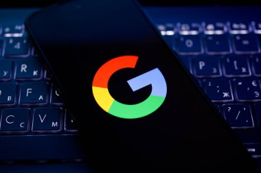 Kherson Reg, Ukrayna 19 Eylül 2024 'te yakın plan Google logosu aydınlatmalı dizüstü bilgisayarın klavyesinde duran akıllı telefon ekranında görüntülendi. 