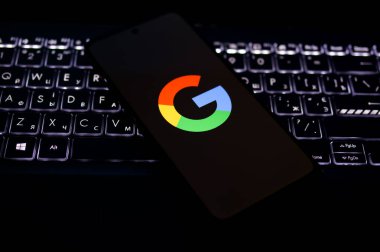 Kherson Reg, Ukrayna 19 Eylül 2024 'te yakın plan Google logosu aydınlatmalı dizüstü bilgisayarın klavyesinde duran akıllı telefon ekranında görüntülendi. 