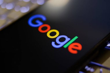 Kherson Reg, Ukrayna 19 Eylül 2024 'te yakın plan Google logosu aydınlatmalı dizüstü bilgisayarın klavyesinde duran akıllı telefon ekranında görüntülendi. 