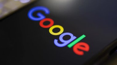 Kherson Reg, Ukrayna 19 Eylül 2024 'te ışıklandırılmış dizüstü bilgisayar klavyesinde yer alan akıllı telefon ekranında yakın plan Google logosu görüntüsü