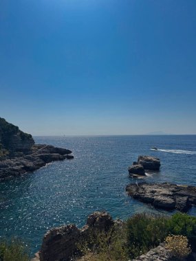 Mavi deniz ufkuyla ve parlak güneş ışığıyla Rocky sahili.