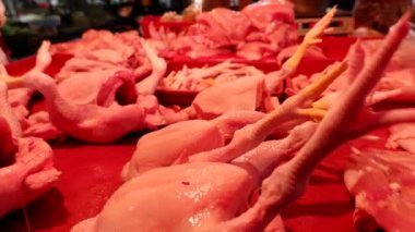 Geleneksel bir pazarda, müşterilere hizmet eden, et kesen ve tartan bir tavuk eti satıcısı..