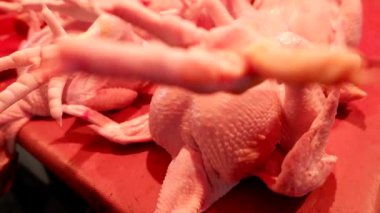 Geleneksel bir pazarda, müşterilere hizmet eden, et kesen ve tartan bir tavuk eti satıcısı..