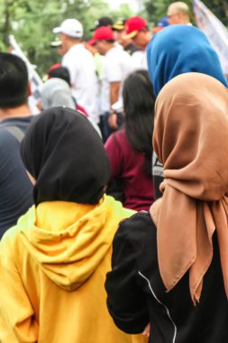 Başörtüsü takan bir grup genç liderin konuşmasını dinledi. 