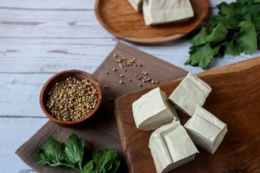 Beyaz arka planda servis edilen tahta kesme tahtasındaki çiğ tofu. 