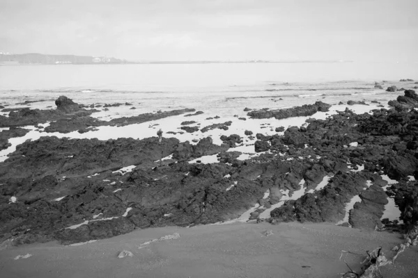 在西班牙吉洪的仁科宁海滩或塞维森海滩 一个男人在低潮时走在岩石上的一个遥远的人影 — 图库照片