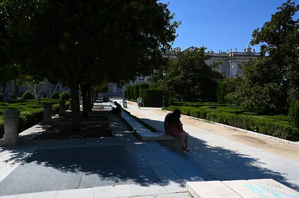 Stock image People sheltering under the trees in Plaza de Oriente, in front of the Royal Place, in the afternoon following hot temperatures in Madrid Spain.