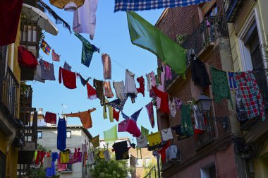 San Cayetano Madrid 'in kutlamaları sırasında dar bir cadde boyunca uzanan Fiesta caddesindeki atkı ve diğer kıyafetlerin renkli manzarası.