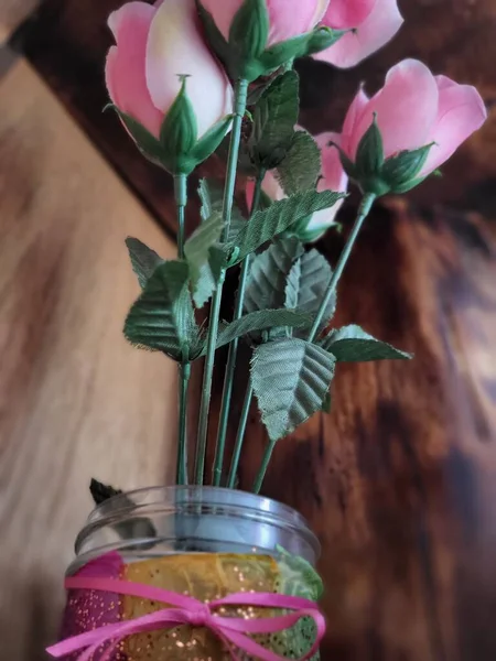 Pink roses in a decorated glass jar