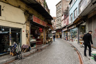 İSTANBUL, TÜRKEYE - 23 Mart 2023: Yerel halk zemin kattaki dükkanlarla dar sokaklarda yürüyor
