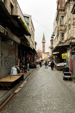 İSTANBUL, TÜRKEYE - 23 Mart 2023: Yerel halk zemin kattaki dükkanlarla dar sokaklarda yürüyor