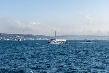 İSTANBUL, TURKEY - 24 Mart 2023: İstanbul arkaplanda köprü ve Golden Horn boğazında modern feribot ile şehir manzarası