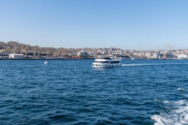 İSTANBUL, TURKEY - 24 Mart 2023: İstanbul arkaplanda köprü ve Golden Horn boğazında modern feribot ile şehir manzarası