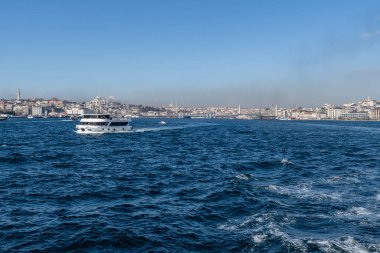 İSTANBUL, TURKEY - 24 Mart 2023: İstanbul arkaplanda köprü ve Golden Horn boğazında modern feribot ile şehir manzarası
