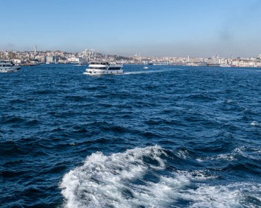 İSTANBUL, TURKEY - 24 Mart 2023: İstanbul arkaplanda köprü ve Golden Horn boğazında modern feribot ile şehir manzarası