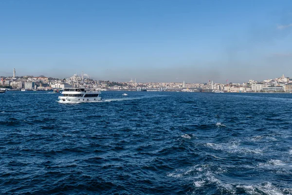 İSTANBUL, TURKEY - 24 Mart 2023: İstanbul arkaplanda köprü ve Golden Horn boğazında modern feribot ile şehir manzarası