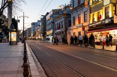 İSTANBUL, TURKEY - 26 Mart 2023: tramvaylı şehir caddesi ve gece vakti inşaat ve pazarlama yapan insanlar