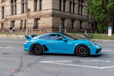 TORONTO, CANADA - 2009 Haziran 2024: Mavi Porsche 911 eski belediye binası yakınlarındaki tarihi şehir merkezi manzarasında sürüyor