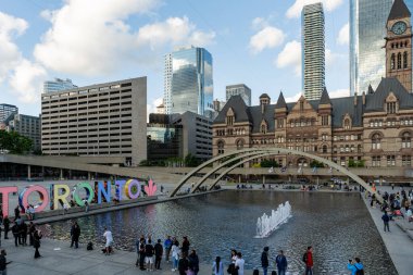 TORONTO, CANADA - Haziran 09, 2024: Nathan Phillips Meydanı 'nda ışıklandırılmış Toronto tabelası ve belediye binası ile çeşme