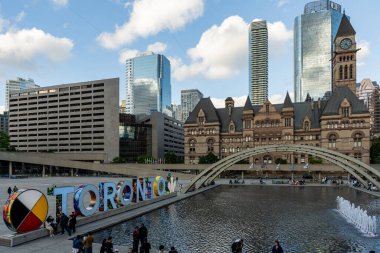 TORONTO, CANADA - Haziran 09, 2024: Nathan Phillips Meydanı 'nda ışıklandırılmış Toronto tabelası ve belediye binası ile çeşme