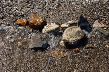 Göl kıyısındaki ıslak taşlar güzel renkli kayalar manzarayı kapatır.