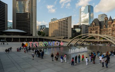 TORONTO, CANADA - Haziran 09, 2024: Nathan Phillips Meydanı 'nda ışıklandırılmış Toronto tabelası ve belediye binası ile çeşme