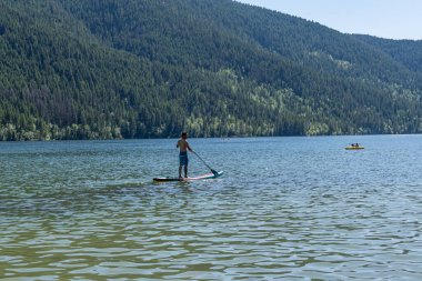 Paul Gölü, Kanada - 06 Temmuz 2024: İnsanlarla dolu Paul Gölü manzarası ve arka planda güzel dağ sıraları