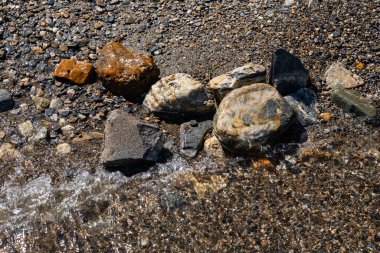 Göl kıyısındaki ıslak taşlar güzel renkli kayalar manzarayı kapatır.
