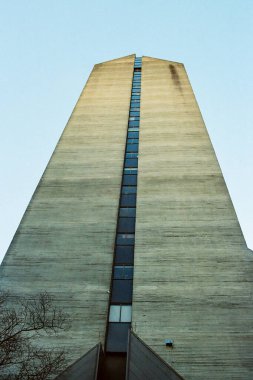 VANCOUVER, CANADA - 24 HAZİRAN 2025: beyaz bulutlu gökyüzünde yüksek bir ofis binasının görüntüsüne bakıyorum. Yapının simetrik bir deseni var..