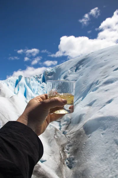 Buzulda bir bardak viski tutan bir adam. Perito Moreno buzulu, Arjantin