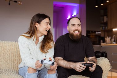 Genç bir çift televizyonun önünde birlikte oturuyor ve uzun bir günün ardından dinleniyorlar. Birlikte vakit geçirmekten ve farklı TV programlarından zevk almaktan ve en sevdikleri oyunları konsolda oynamaktan mutlular. İlgi alanlarını paylaşmak için harika bir yol.