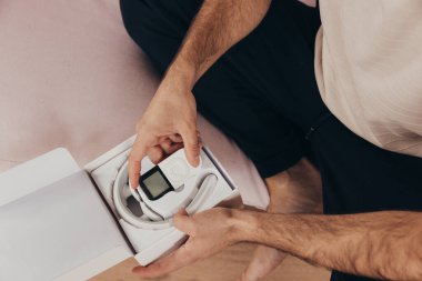 Genç adam evde yeni elektrikli masaj cihazını ve uzaktan kumandasını açıyor. Denemek ve uzun bir günün ardından kas gerilimini nasıl azaltacağını görmek için sabırsızlanıyor..