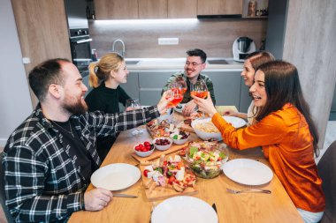 A group of friends on a lovely day gathered together to enjoy time together, eating and laughing. Toasting with glass of Apperol. High qualtiy photo. clipart