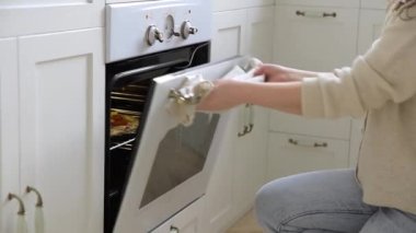 Genç bayan fırından yeni pişmiş lezzetli bir pizza alır. Beyaz dolaplı, ferah İskandinav tarzı bir mutfakta beyaz bir fırında ev yapımı pizza..
