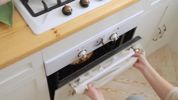 年轻女子的头像是从白色的老式烤箱里拿出一个刚烹调好的美味披萨 在家做的比萨饼在一个白色的烤箱里 在一个轻盈宽敞的斯堪的纳维亚风格的白色厨房里烹调 — 图库视频影像