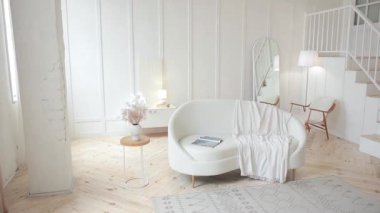 Beyaz önkol kemikli deri koltuklu şık bir oturma odası. Beyaz duvarları, ahşap zemini, ikinci kata çıkan ahşap merdivenleri ve oval aynası olan minimalist geniş bir oda. Boş boşluk.