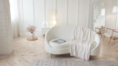 Beyaz oval deri kanepeli şık bir oturma odası. Beyaz duvarları, ahşap zemini, ikinci kata çıkan ahşap merdivenleri ve oval aynası olan minimalist geniş bir oda. Kimse..