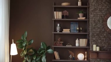 Tuğla şöminenin yanında kitapları ve dekorasyonu olan kahverengi raflar ve modern şık bir oturma odasında kahverengi duvarları ve ahşap zemini olan saksı bitkileri. Ev kütüphanesinde kitaplarla dolu. Kimse..