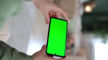 Dikey video. El kamerasının modeli. Anahtar yeşil ekranlı yatay akıllı telefon kullanan bir kadının el görüntüsünü kapat. Chroma tuşu, yayın hizmetleri uygulamaları için bir model oluşturur. Seçici odak.